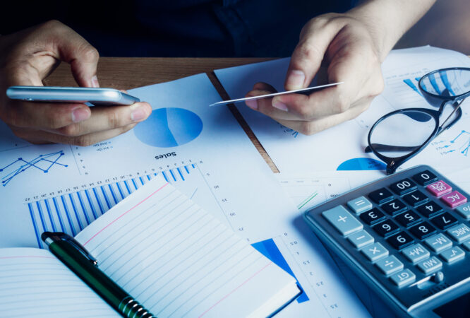 Asian hand man using mobile phone and credit for e commerce online on home office.accessories  document chart notebook eyeglasses pen on wood table background.shopping online.financial.saving concept.