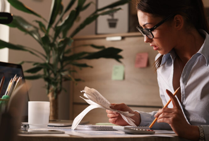 Female accountant calculating tax bills while working on finances in the office.