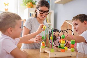 Preschool teacher with children playing with colorful wooden did